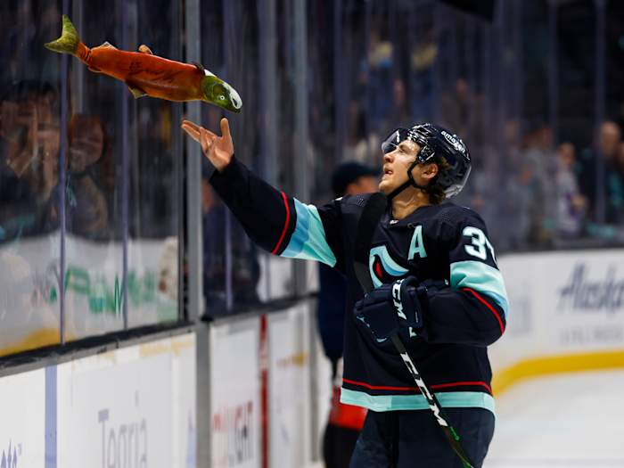 Seattle Kraken center Yanni Gourde (37) tosses a toy sockeye salmon to fans following a 4-0 victory against the Vancouver Canucks.